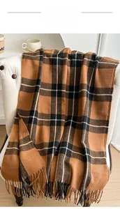 Detail of classic plaid scarf with fringe edge draped over a white chair in home setting