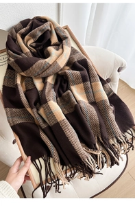 Close-up of thick plaid scarf featuring long tassels and soft brushed texture on a chair