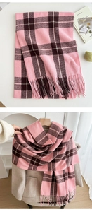 Detail of pink and brown plaid scarf featuring soft cashmere-like texture and tassel fringe