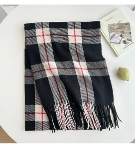 Detailed view of the classic black and white plaid scarf with red stripes and fringe trim