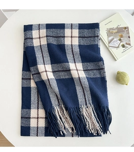 Close-up of blue and white plaid scarf with long tassels on a minimalist table