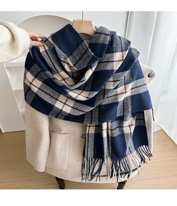 Detail of navy and beige plaid scarf with tassels styled on a cream winter coat