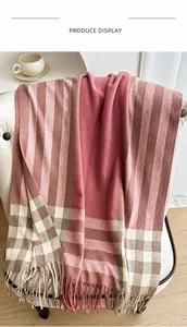 Close-up of pink and brown plaid scarf with long fringe draped on a white chair