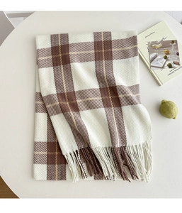 Detail of classic plaid scarf with soft fringe texture on a minimalist white table