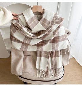 Detailed close-up of beige plaid scarf with soft fringe tassels on a coat