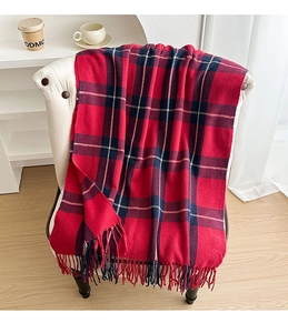 Detail of red and blue plaid scarf with fringes draped over a white chair in a cozy room