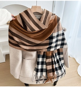 Detail of checkered plaid shawl with long fringes draped over a beige wool coat