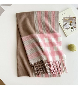 Close-up of thick plaid scarf texture with soft fringe edges in pink and brown