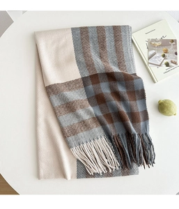 Close-up of beige and grey plaid scarf with soft fringe edges on a white table