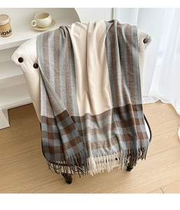 Detail of soft plaid scarf with fringe tassels on a vintage white sofa background