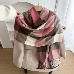 Soft pink and brown checkered thick scarf with fringe displayed on a beige wool coat