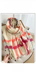 Detail of thick cashmere-like plaid scarf with soft fringe on a cozy white chair