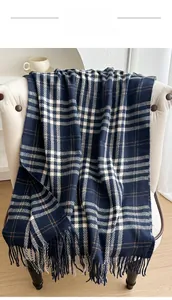 Detailed view of navy blue plaid scarf with long tassels draped over a cozy chair