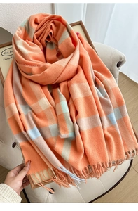 Detail of soft plaid scarf with thick orange and beige check patterns and long fringe