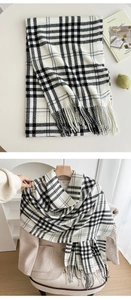 Detail of soft black and white plaid scarf with fringe on a beige wool coat