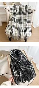 Detail shot of black and white plaid scarves with tassels on a cozy indoor chair