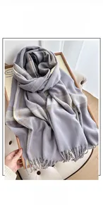 Close-up of thick grey plaid scarf texture with soft cashmere-like tassels on a tray