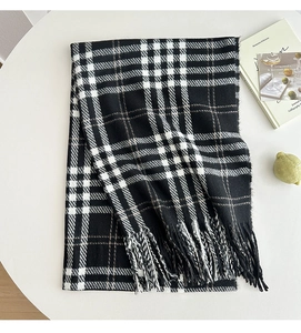 Detail of classic black and white plaid scarf featuring thick tassels and soft warm texture