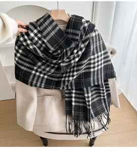 Close-up of black and white checkered scarf with fringe on a beige wool coat