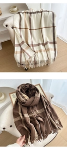 Detail of soft plaid scarf with tassels on cozy armchair in a minimalist room