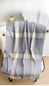 Detail view of purple checkered scarf with long tassels on a cozy white chair