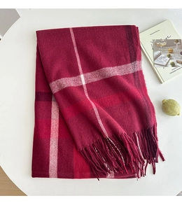 Detail of red and white plaid thick scarf texture with soft fringe edges on a table