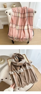 Close-up of thick plaid scarves with fringes in soft pink and classic brown patterns