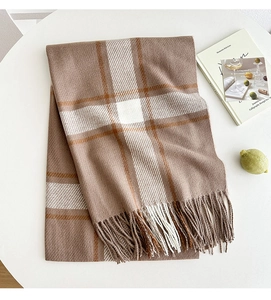 Detail of soft winter scarf with brown and orange plaid pattern and fringe edges