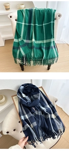 Close-up of green and navy blue plaid scarf with decorative tassels and soft texture