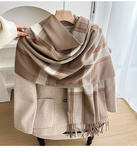 Detail of a thick plaid scarf with tassels, featuring coffee and camel checkered pattern