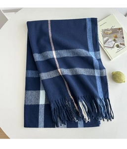 Detail of a thick plaid scarf with navy blue checkered patterns and soft fringe edges