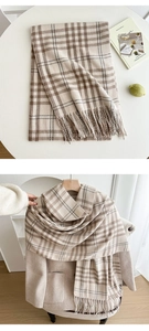 Close-up of beige and brown plaid scarf with tassels styled on a wool coat