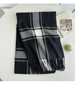 Detail of classic black and white plaid scarf with soft fringe tassels on a table