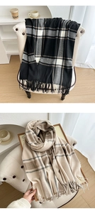 Close-up of thick plaid scarf with tassels in neutral tones and soft cashmere-like texture