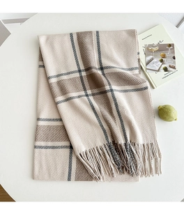Detail of soft beige plaid scarf with fringed edges and thick woven texture for winter