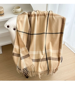 Close-up of thick beige plaid scarf with fringes draped on a white leather chair