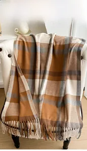 Close-up of thick plaid scarf with tassels draped on chair in cozy indoor setting