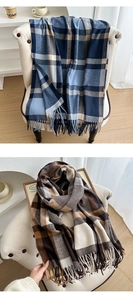 Detail view of plaid tassel scarves in blue and brown schemes on a minimal white chair