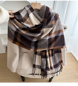 Detail of thick checkered scarf with long fringe texture over a beige wool coat