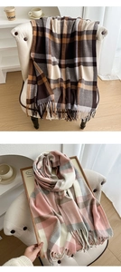 Detail of soft plaid scarves with fringe in coffee and pink colorways on a sofa