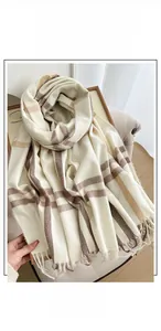 Detail of plaid faux cashmere scarf with tassels on a chair in soft indoor lighting