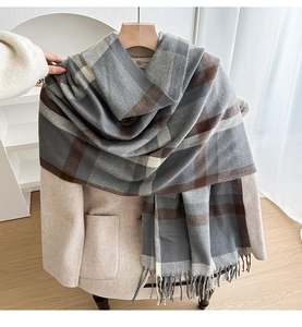 Detail of plaid scarf with tassels styled on a beige blazer in a bright indoor setting