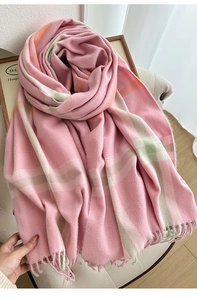 Macro shot of soft pink plaid cashmere-feel scarf with elegant fringe detail on a chair
