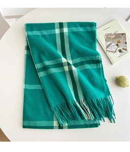 Detail view of dark green cashmere-like scarf with classic plaid patterns and fringe