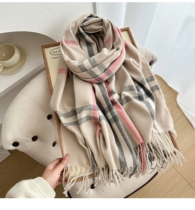Close-up of beige plaid cashmere-like scarf with fringe on a wooden frame