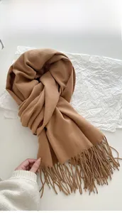 Detail of camel cashmere-feel scarf featuring soft woven texture and long fringe tassels
