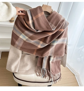 Detailed view of British style checkered cashmere-like scarf with tassels on beige coat