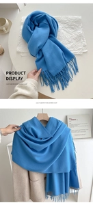 Detail of blue imitation cashmere scarf with tassels styled on a brown coat