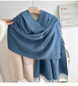 Close-up of thick gray-blue solid scarf featuring long tassels and soft cashmere-like texture