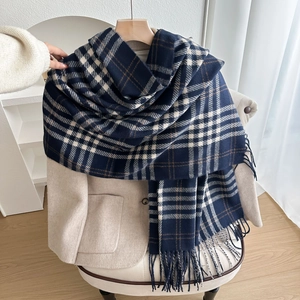 Thick plaid scarf in navy blue and brown with tassels draped over a beige wool coat